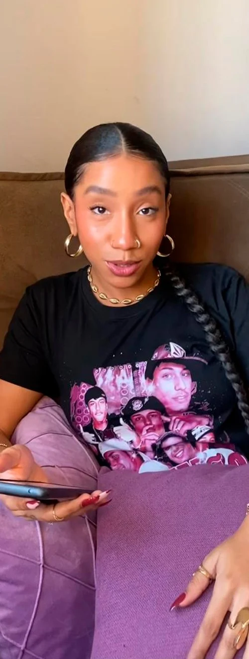 Shawty usando a camisa Felipe Boladão em cena do clipe, sentada no sofá